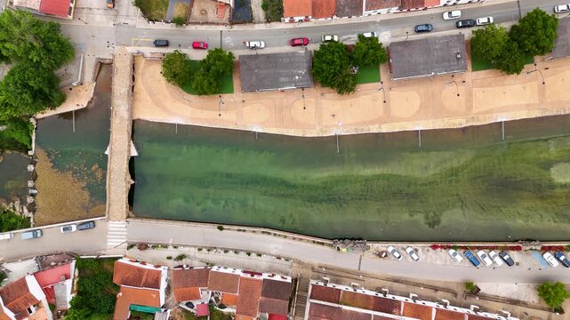 Aerial view of Puente de Piedra crossing the Galindon River with a promenade and rooftops in San Nicolas del Puerto, Andalucia, Spain.