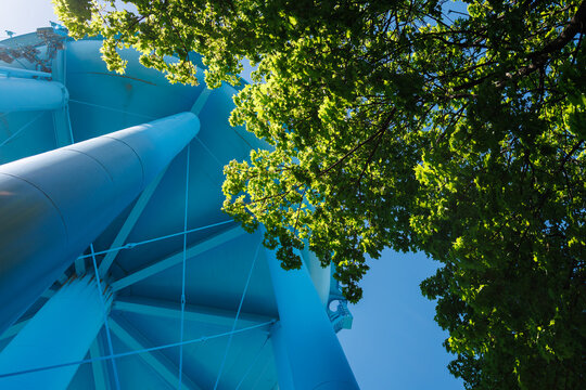 Water tower surrounded by green leaves and blue sky during daytime in a park setting