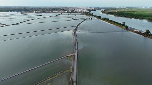 Aerial view of Isla Minima flooded rice fields and the Guadalquivir river with a town in the distance in La Puebla del Rio, Andalucia, Spain.