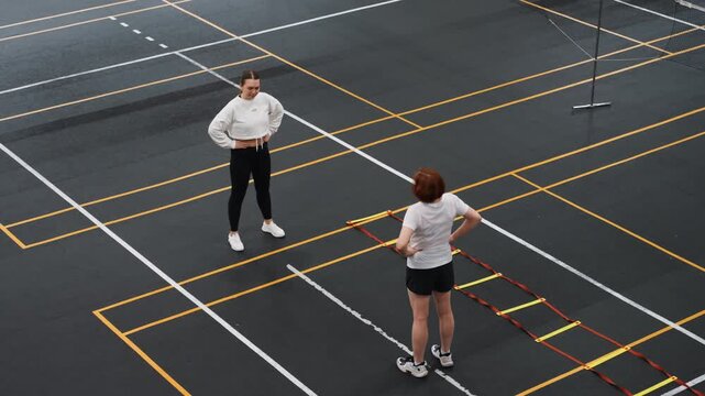 Coach discusses footwork techniques. Instructor provides feedback on court movements. Indoor sports professional evaluates player foot positioning and offers guidance for improvement