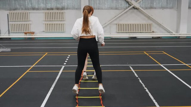Partner ladder drill improving badminton court positioning, two athletes executing lateral steps and split stance with coach guidance, indoor court lines visible, precise timing and teamwork focus
