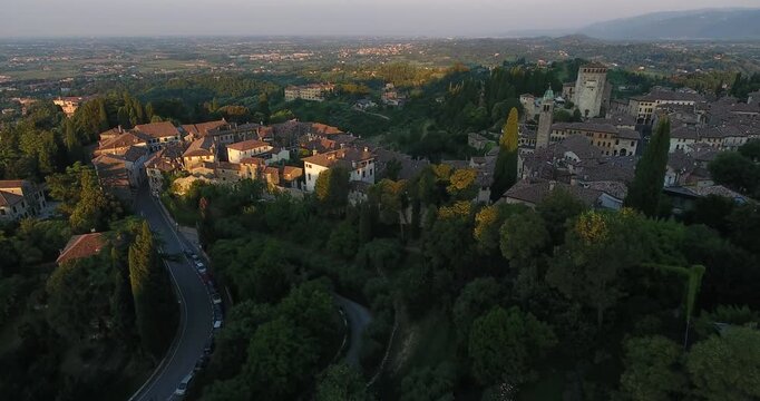 Aerial view of the historic center with terracotta rooftops and lush green hills in Asolo, Veneto, Italy.