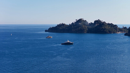 Fototapeta premium Luxury Yachts Anchored in Blue Mediterranean Waters Near Portofino Coastline