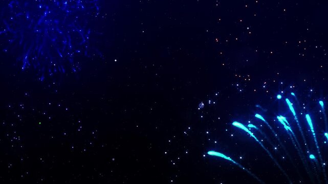 Stunning vibrant fireworks explode across a deep starry night sky creating a festive celebration atmosphere for New Year