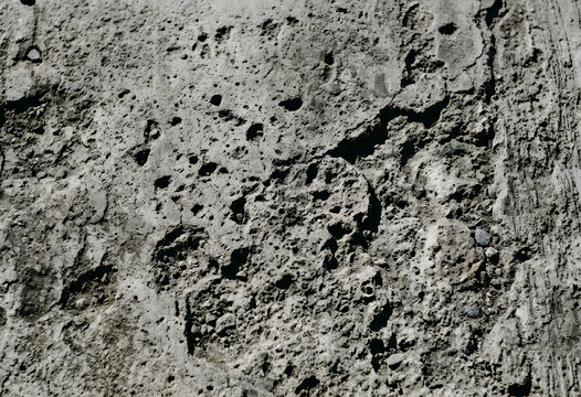 Rough weathered grey concrete surface with deep pits