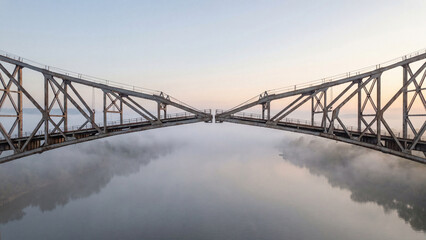 Fototapeta premium Aerial view of a large metal drawbridge opening over a river in thick fog