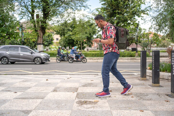 Fototapeta premium Indonesian Man Walking While Using Smartphone Outdoors