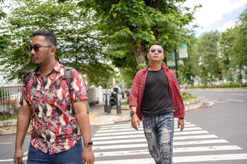 Obraz premium Two Asian Indonesian Men Walking Together in City Park