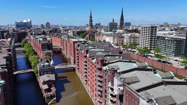 Hamburg, Germany - 28 May 2026: Aerial view of Speicherstadt warehouse district with its historic red brick buildings, canals, and church spires under a clear blue sky.