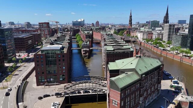 Hamburg, Germany - 28 May 2026: Aerial view of the historic Speicherstadt warehouse district with red brick buildings, narrow canals, and bridges under a clear blue sky.
