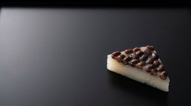 Minimalist composition of a traditional Minazuki wagashi cake on a smooth matte black lacquered tray