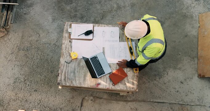 Construction, documents and above of man for planning, building design and inspection. Civil engineering, supervisor and person with paperwork and laptop for floorplan, blueprint and infrastructure