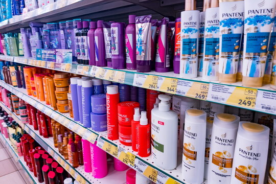 Shelves stocked with various hair care products including Pantene shampoos and conditioners, colorful bottles from brands like LOr&eacute;al, Dove, and more.  
