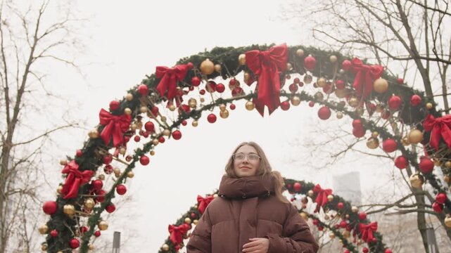 Girl watches decorations. Female observer looks at seasonal ornaments with delight and admiration. Girl scrutinizes intricately decorated holiday symbols with evident fascination and joy