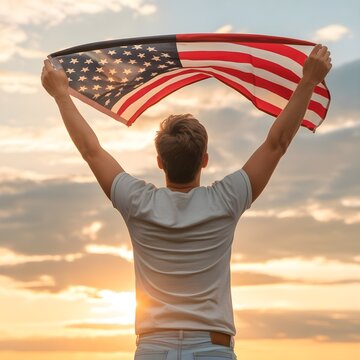 Joven de espaldas sosteniendo con orgullo la bandera de Estados Unidos al atardecer