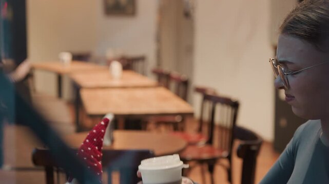 Woman drinks alone. Lonely woman quietly enjoys warm beverage. Single woman in cafe appears exhausted yet thoughtful. Solitary woman seated quietly in peaceful cafe sip her steaming hot drink