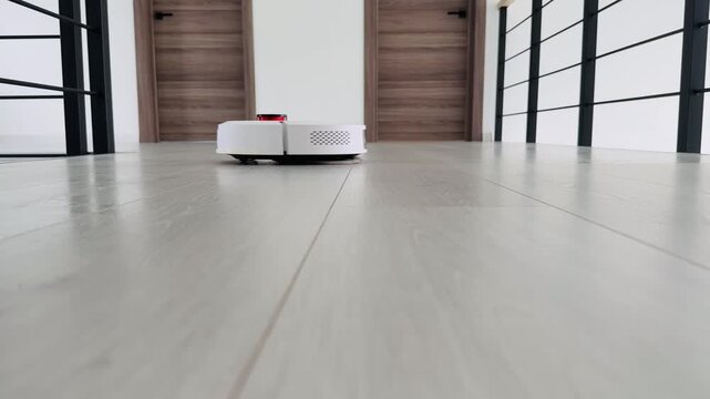 Robot vacuum cleaner navigating modern hallway with wooden doors and smooth flooring