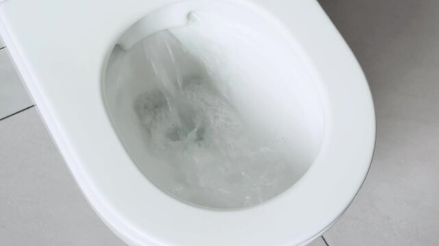 Toilet bowl interior showing clear water reservoir and smooth ceramic texture in bathroom setting