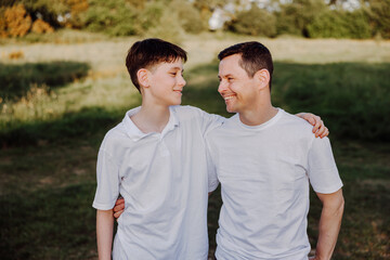 Obraz premium Father and teenage son sharing warm moment in sunny countryside park