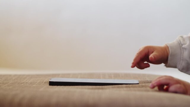 Child's finger pressing, scrolling, tapping on  mobile phone screen. Little child learns to use new technologies.  Baby pressing with finger on phone touch screen, close-up and soft focus.