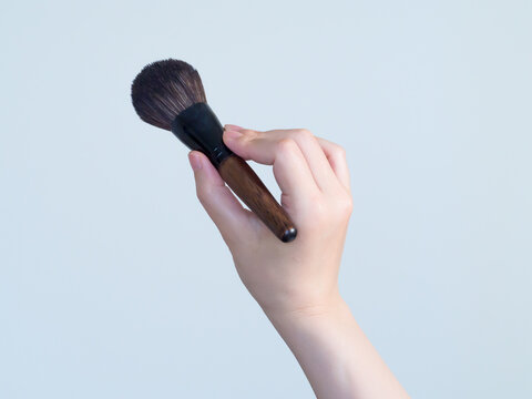 メイクブラシを持つ手元