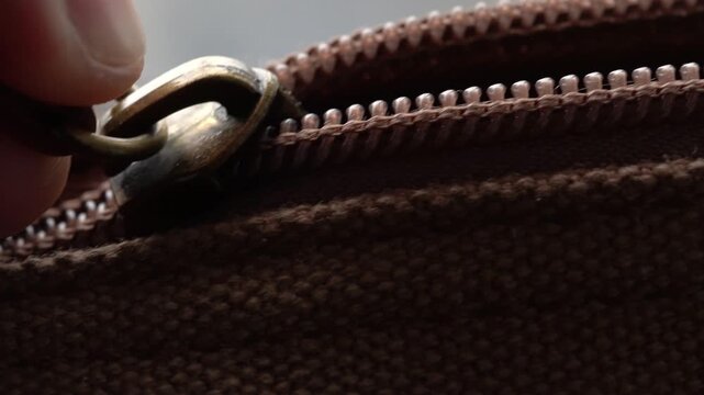 Opening a zip on a brown bag in macro view, zip opening by hand, vintage bag
