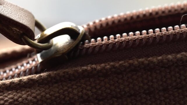 Opening zip on brown bag in macro view, zip opening by hand, vintage bag close up
