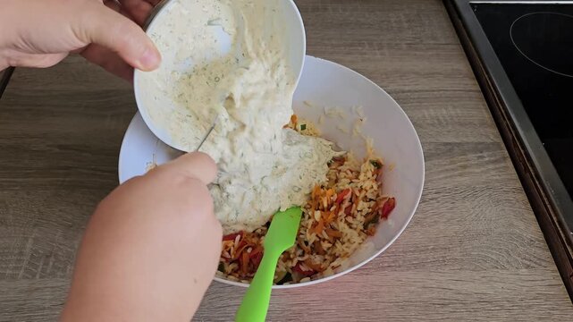 Pouring creamy yogurt dressing into rice salad