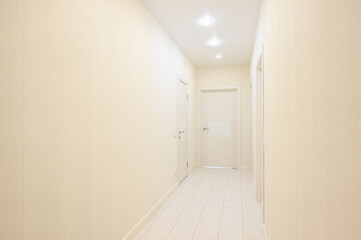 Fototapeta premium narrow hallway with cream-textured walls, white tiled floor, recessed ceiling lights, and three closed white interior doors along the sides