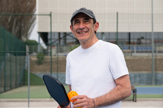 Senior man smiling outdoors ready for a pickleball game on the court