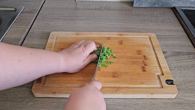 Woman's hands cutting fresh green onions