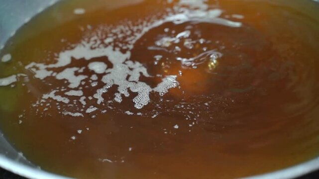 Meatballs are formed with a spoon over hot oil, a close-up of traditional street food preparation for a glimpse of Asian cuisine.