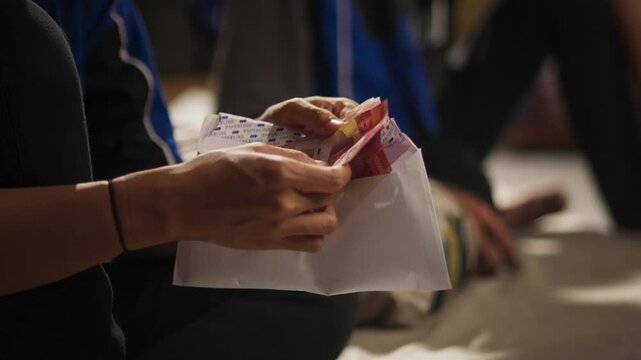 Hand Opening Envelope Containing Indonesian Rupiah Banknotes