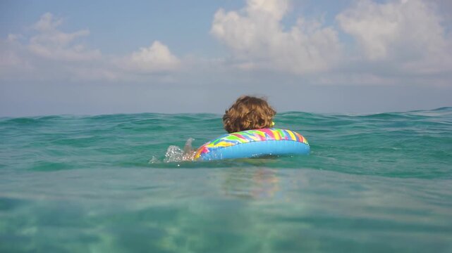 A happy child is having fun in the sea during the summer holidays. Slow motion