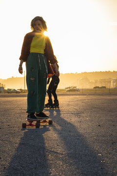 Young woman skateboarding enjoying golden hour backlighting