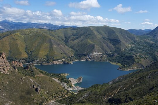 Large blue lake, surrounded by green mountains and hills, under a cloudy sky, reservoir, Embalse de Canales, Canales dam, Sierra Nevada, near G&uuml;&eacute;jar Sierra, Granada province, Andalusia, Spain