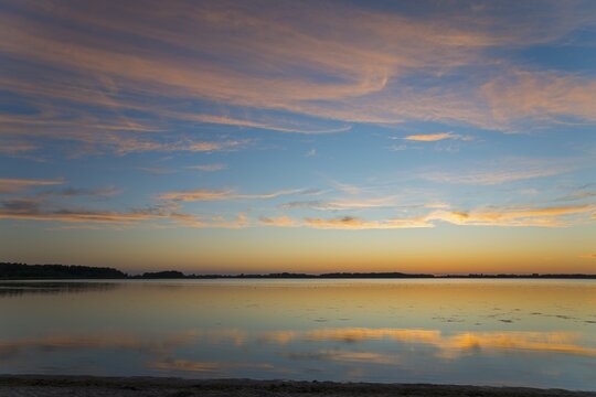 Peaceful sunrise over a smooth lake with pastel-coloured sky and reflections, sunset, Zatoka Wrzosowska, Lake Fritzow, Dziwnow, Zachodniopomorskie, West Pomerania, Poland