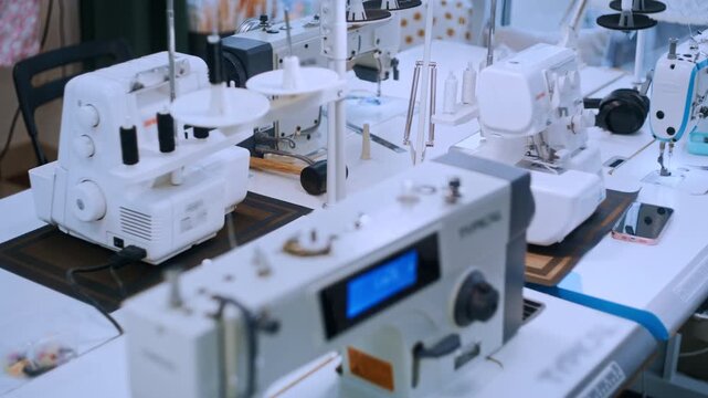 Many sewing machines standing on tables in an empty tailor studio or garment factory