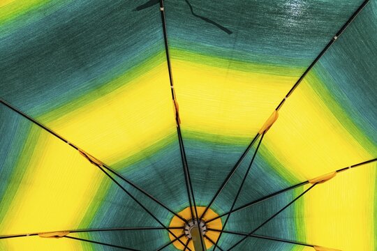 Green and yellow parasol on the beach of Straccoligno, near Capoliveri, Elba, Tuscan Archipelago, Tuscany, Italy