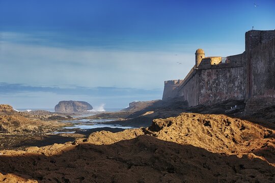 Ragged rocks at low tide, coastline with view of the old city wall of Essaouira, Unesco World Heritage Site, Morocco