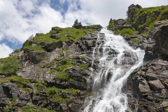 A gushing waterfall cascades over rocky slopes under the blue sky, Capra Waterfall, Goat Waterfall, Transfogarasan High Road, Transfagarasan, Transfăgărășan, Făgăraș Mountains, Fagaras, Transylvania, Transylvania, Transylvania, Ardeal, Transylvania, Carpathians, Romania
