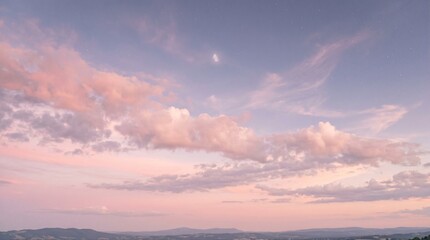Obraz premium Serene landscape with pink clouds and blue sky at sunset over mountains