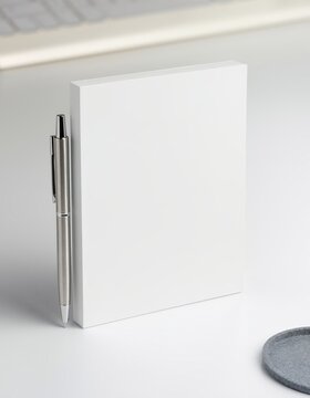 Blank notebook with silver pen on white desk