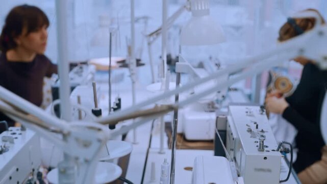 Professional women sew clothes on industrial machines in a garment factory