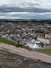 Obraz premium Aerial View of Dundee Coastal Town with Rocky Shoreline and Cloudy Sky
