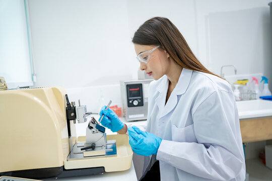 Scientist in protective gear meticulously works with a laboratory microtome instrument