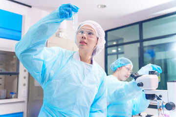 Fototapeta premium Scientists in protective gear conduct research with test tubes and microscopes in a lab