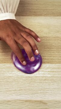 Purple translucent slime toy on wooden table, child's hand playing with gooey sensory putty, satisfying ASMR texture video for kids entertainment