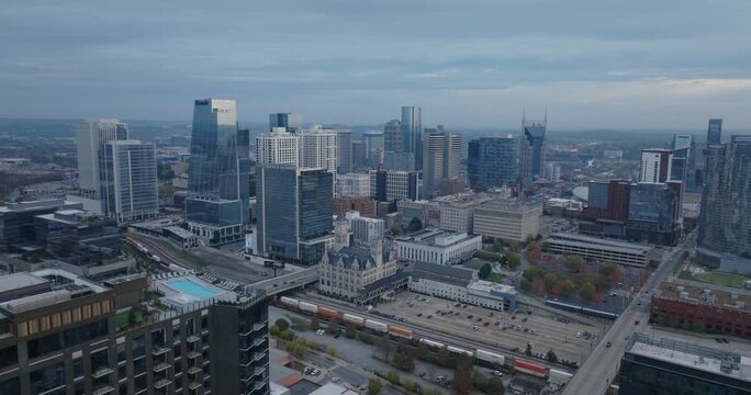 Nashville skyline aerial view at dusk with downtown buildings, trains, and cloudy sky in motion.