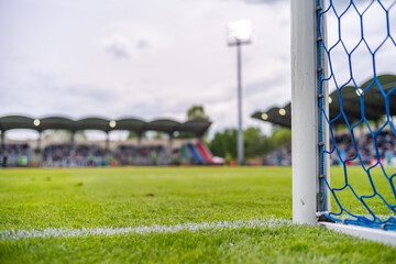 Close-up of soccer goalpost and net with white field line, stadium and crowd in background, real sports action atmosphere.m.pl © Dziurek